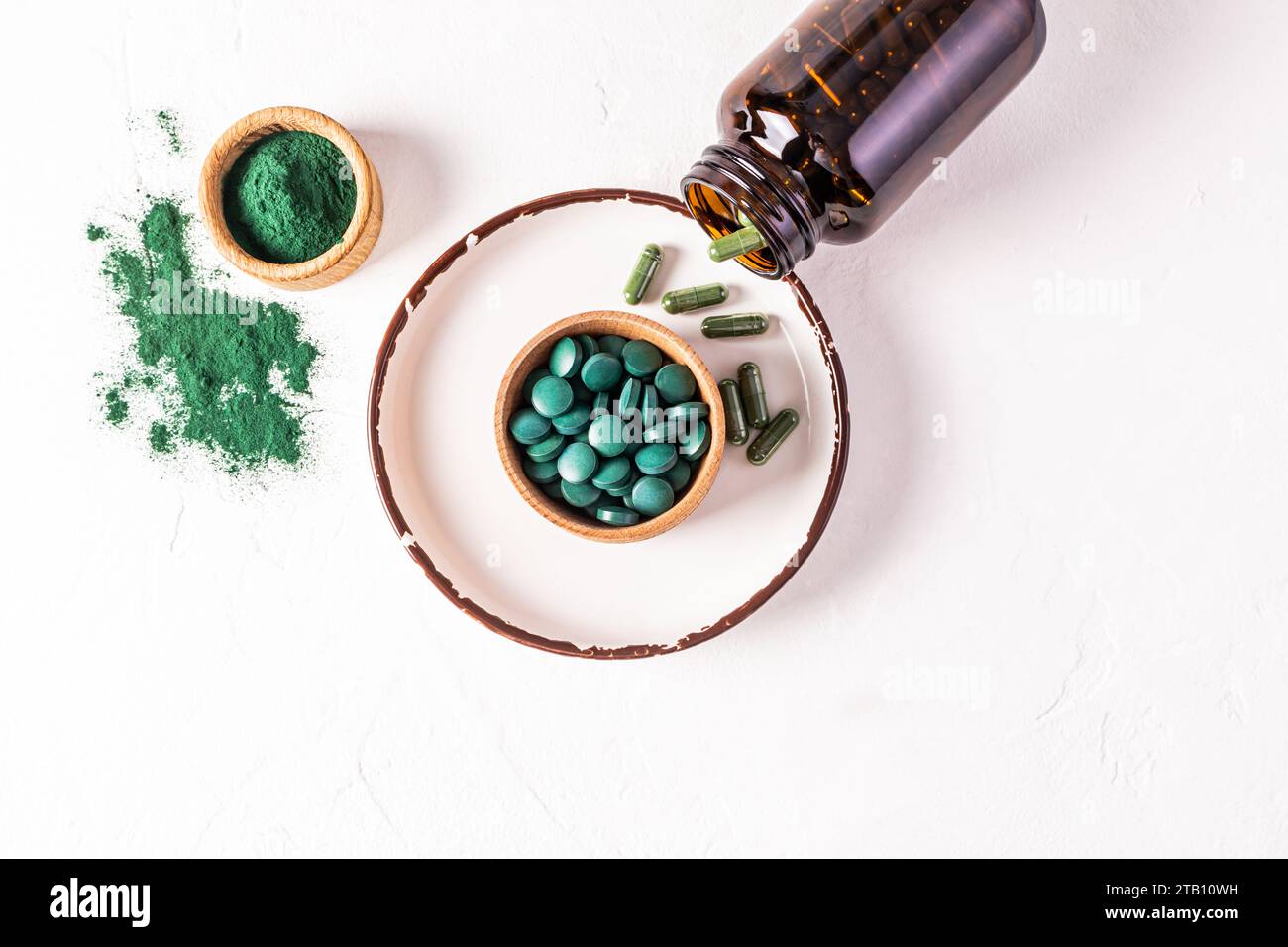 Round bluegreen natural spirulina algae tablets and powder in bowl on