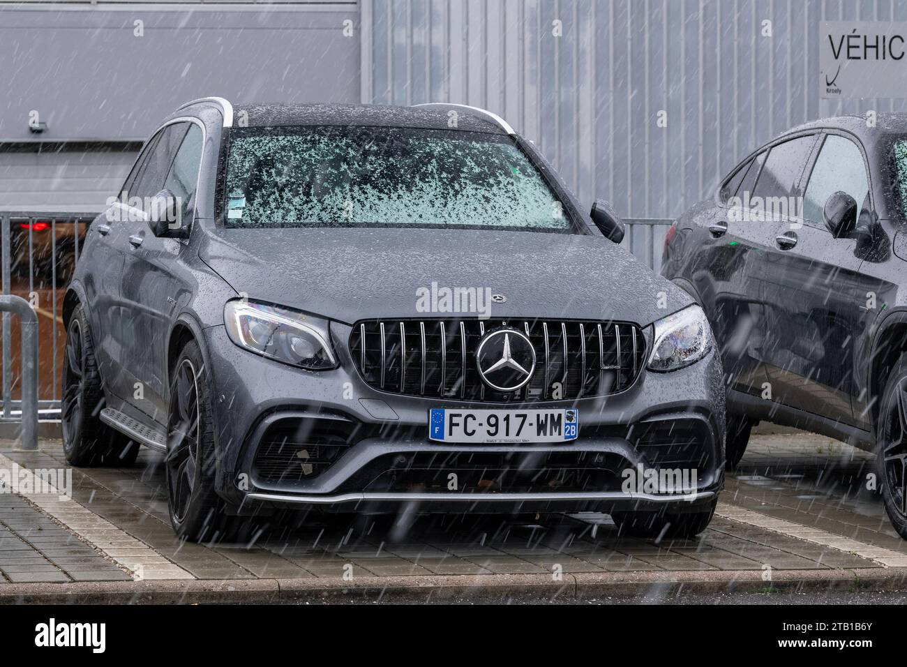 Laxou, France - Grey Mercedes-AMG GLC 63 parked on a street under a snow fall. Stock Photo