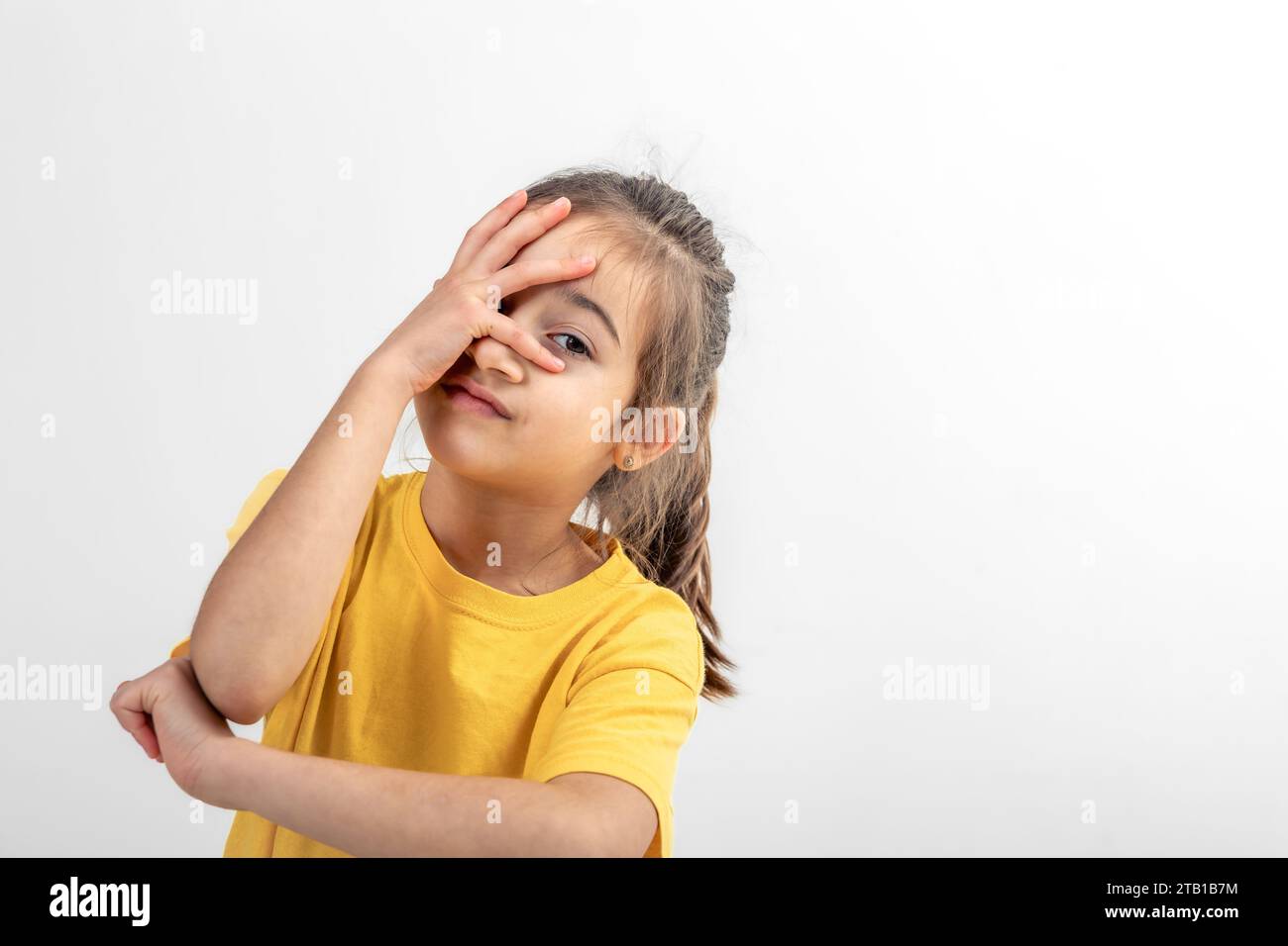 A little girl holds her palm on her face on a white background isolated ...