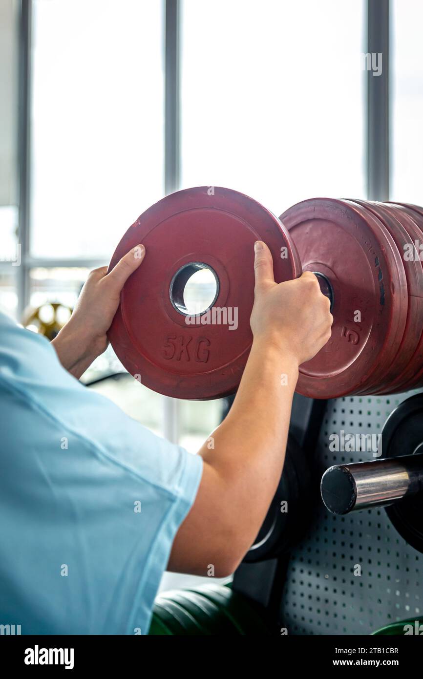 Putting Weight On Object A muscular sportswoman putting weight plates in a gym for bodybuilding ...