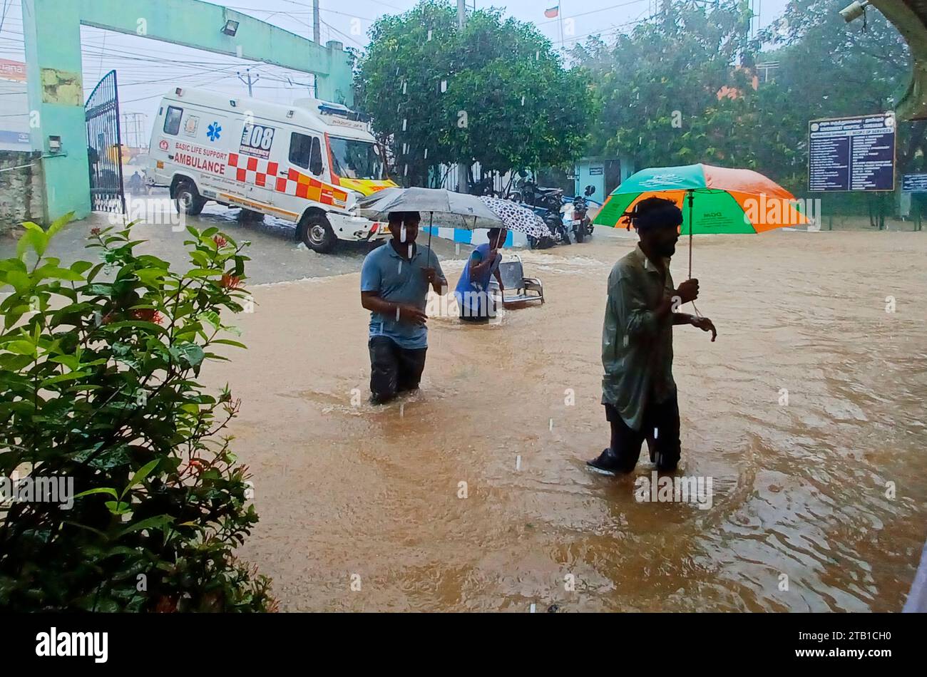 People walk outside the Tambaram Government Hospital flooded
