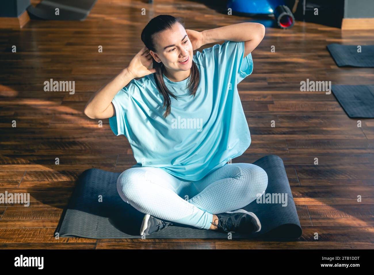 Young woman sitting on a mat in a fitness center, doing yoga and ...