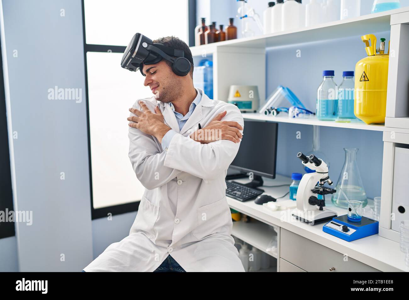 Young hispanic man working at scientist laboratory wearing vr glasses ...