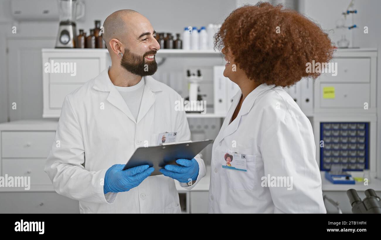 Two smiling scientists in the lab, engrossed in a lively chat while ...