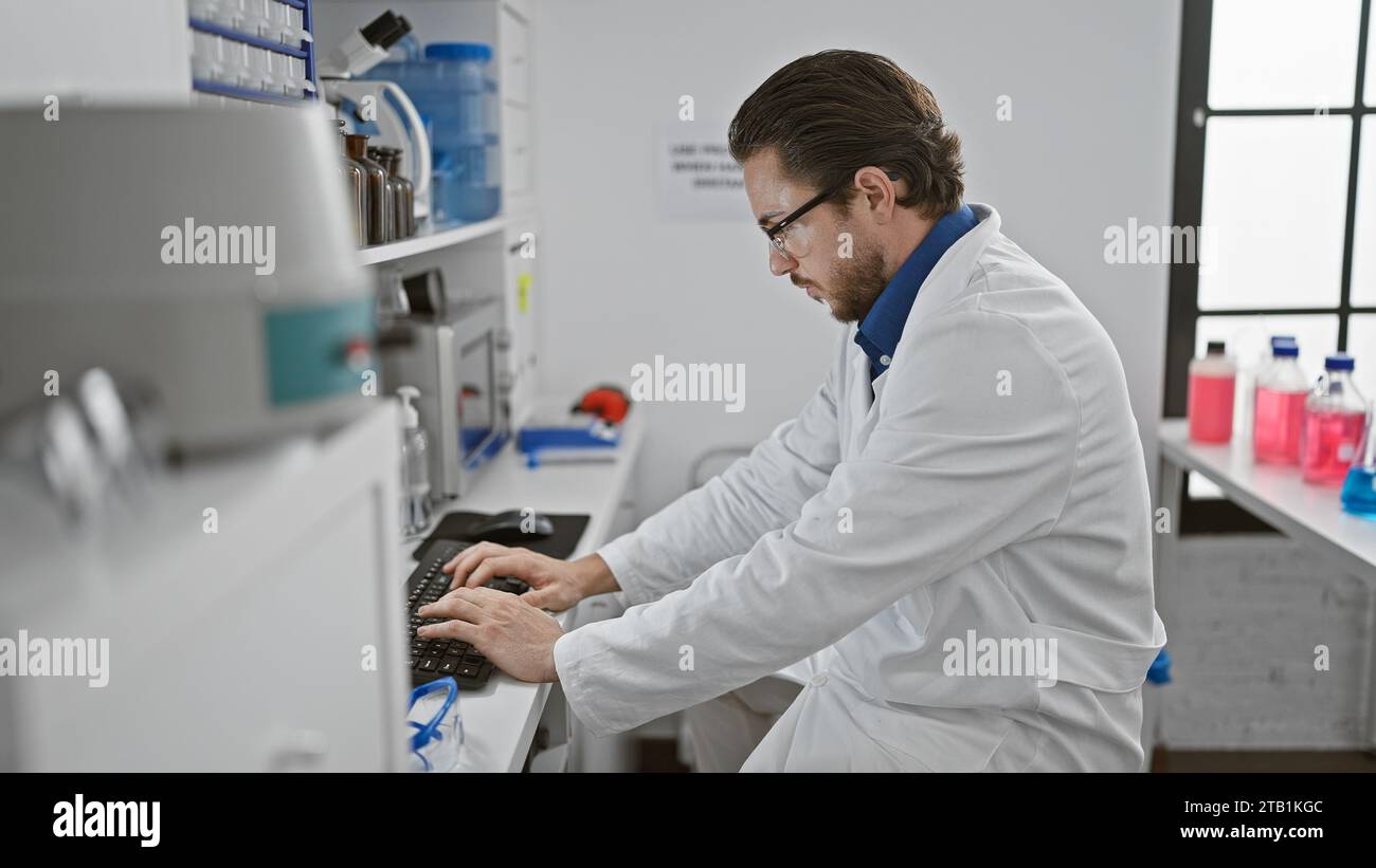 Young hispanic man scientist using computer at laboratory Stock Photo
