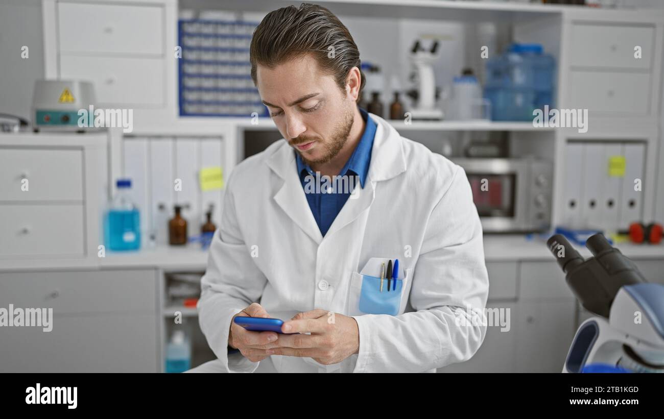 Young hispanic man scientist using smartphone at laboratory Stock Photo
