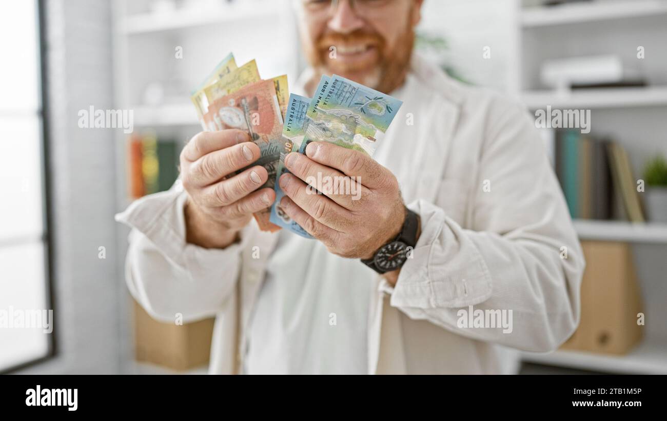 Cheerful caucasian business man confidently counting australian dollars at office, radiating success and happiness Stock Photo