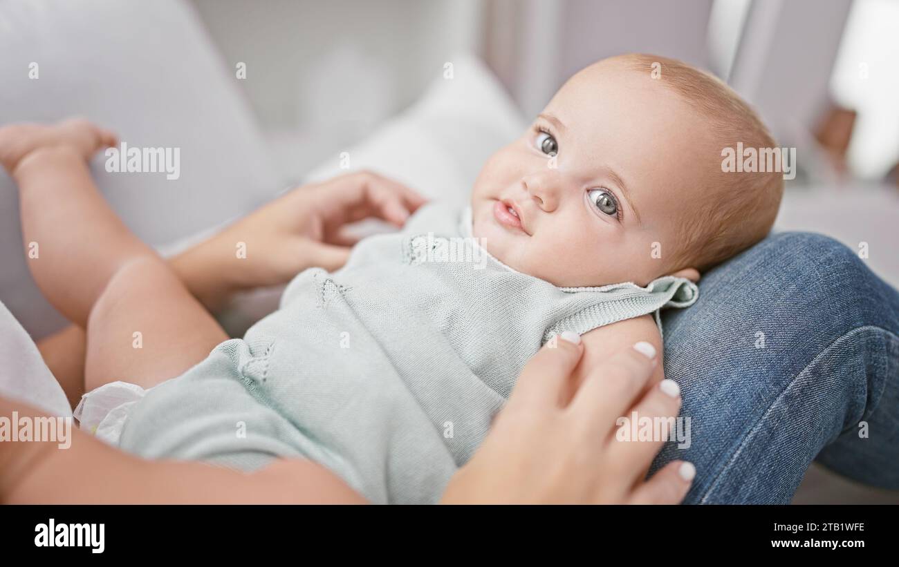 Joyful mother sitting on the living room sofa, having a fun playtime with her lovely daughter, their smiles radiating positive energy, cherishing thei Stock Photo
