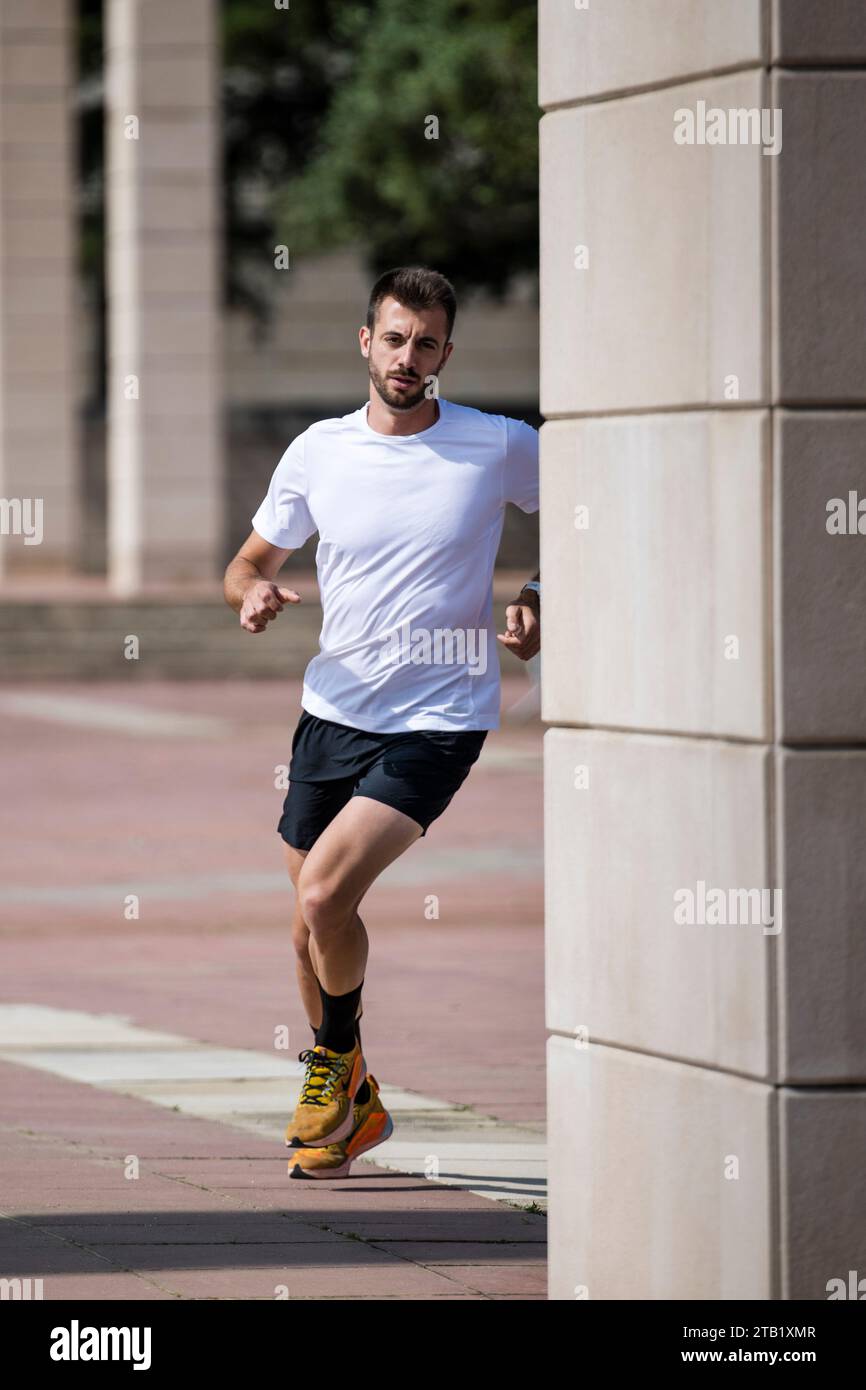 Determined fitness male athlete runner turning a corner in the street. Stock Photo