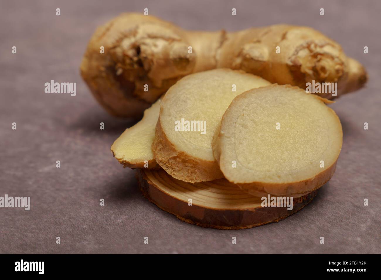 ground ginger in a wooden spoon with fresh ginger root Stock Photo