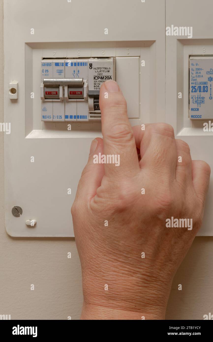 Woman pushing lever on fuse box to save energy Stock Photo