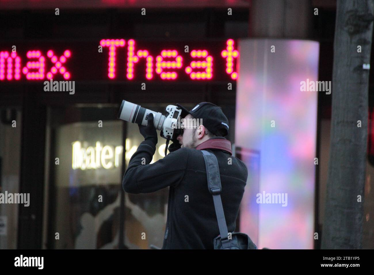 A man with a digital camera is capturing a stunning shot of a cityscape with a computer monitor visible in the foreground Stock Photo
