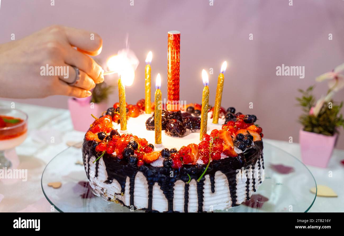 Mother's hand lighting candles in birthday cake Stock Photo