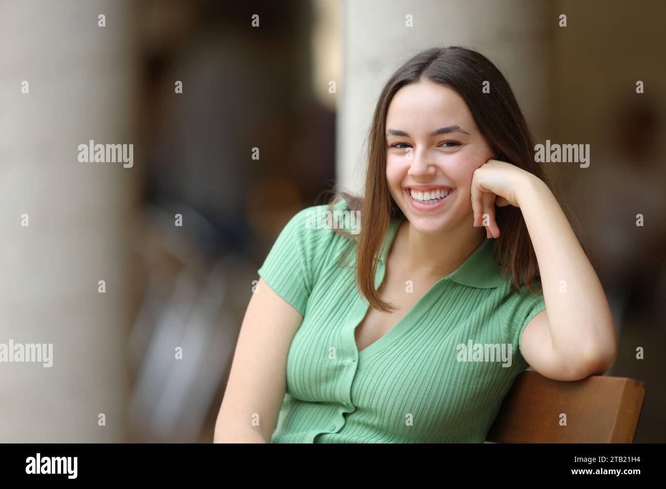 Happy woman laughing looking at camera sitting on a bench in the street Stock Photo