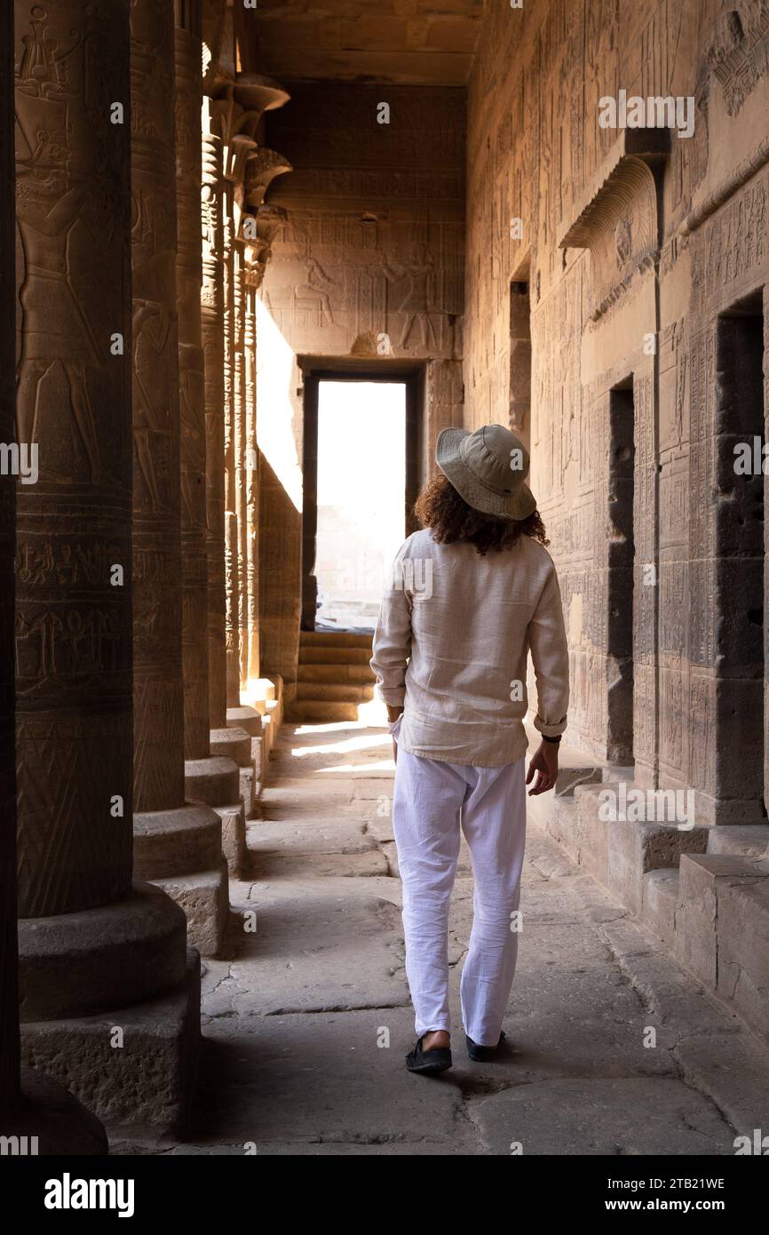 Man with curly hair and hat, exploring old egyptian temple, Aswan Stock Photo