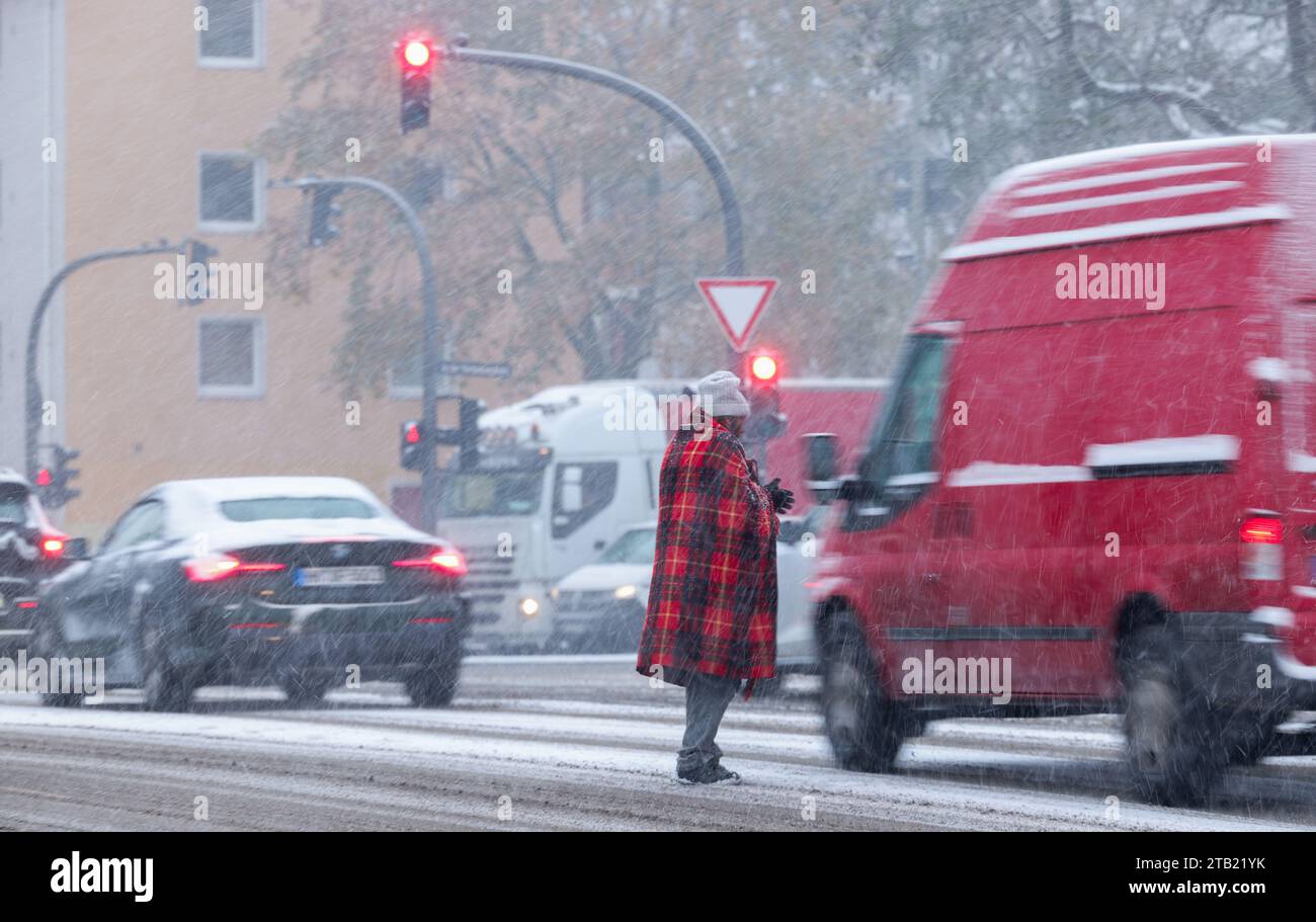 Hamburg, Germany. 04th Dec, 2023. A man stands at a traffic light in the snow with a blanket between waiting cars and asks for alms. Credit: Christian Charisius/dpa/Alamy Live News Stock Photo