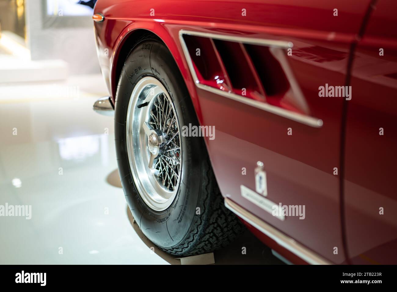 MODENA, ITALY - APRIL 21, 2022: Detail of Ferrari 275 GTS red sports car in Museum Enzo Ferrari Modena focused on the wire wheel knock-off spinner Stock Photo