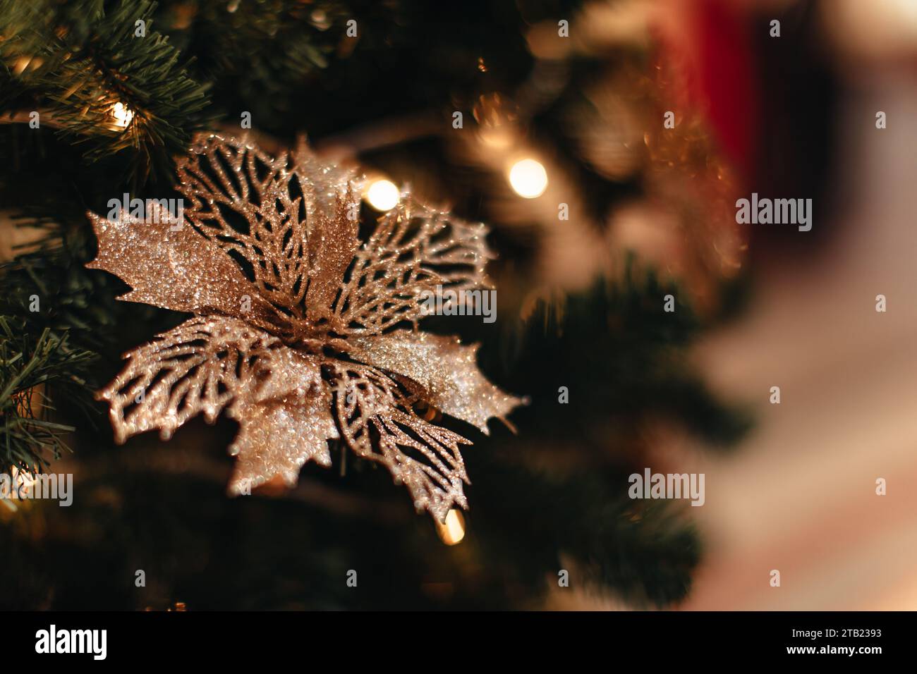 Golden flower hanging on a Christmas tree with flashing golden lights