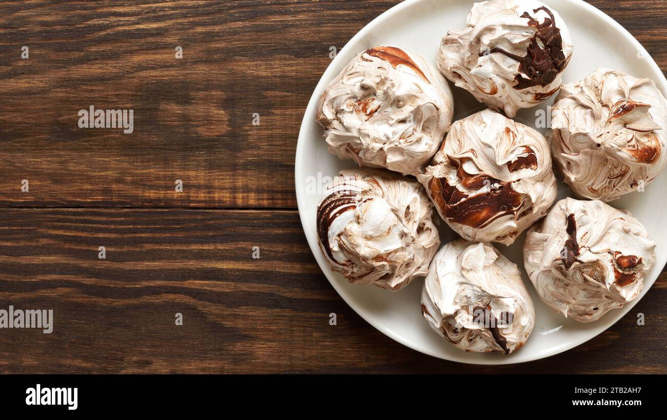 Close up view of chocolate meringue cookies on plate over wooden background with free space. Top view, flat lay Stock Photo