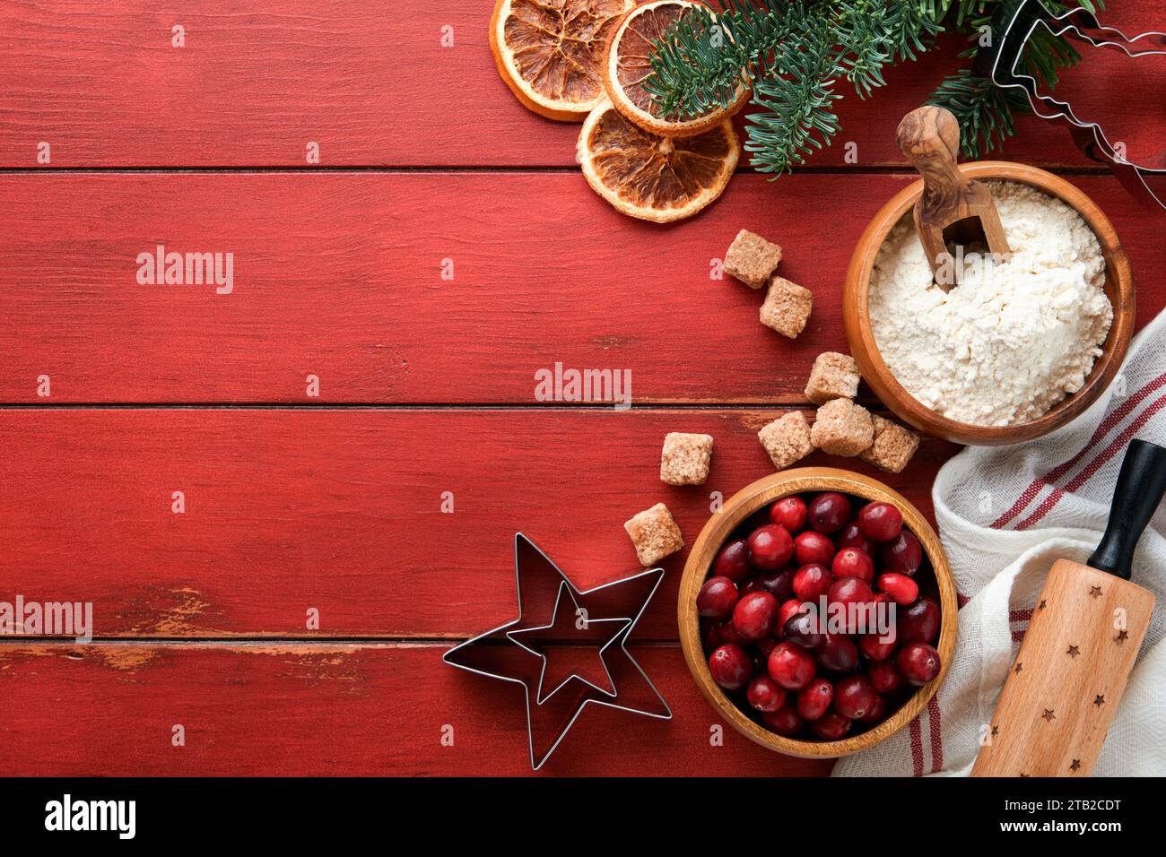 Christmas culinary background with ingredients for cooking christmas baking cranberries, sugar, cinnamon and Christmas tree branches on rustic old red Stock Photo