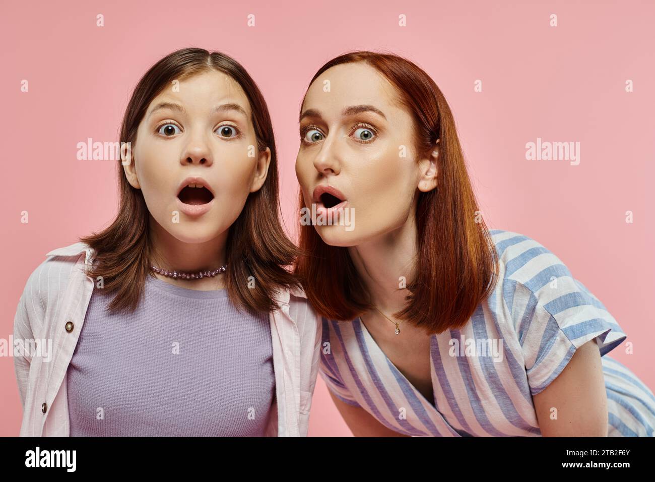 amazed mother and teenage daughter with open mouths looking at camera