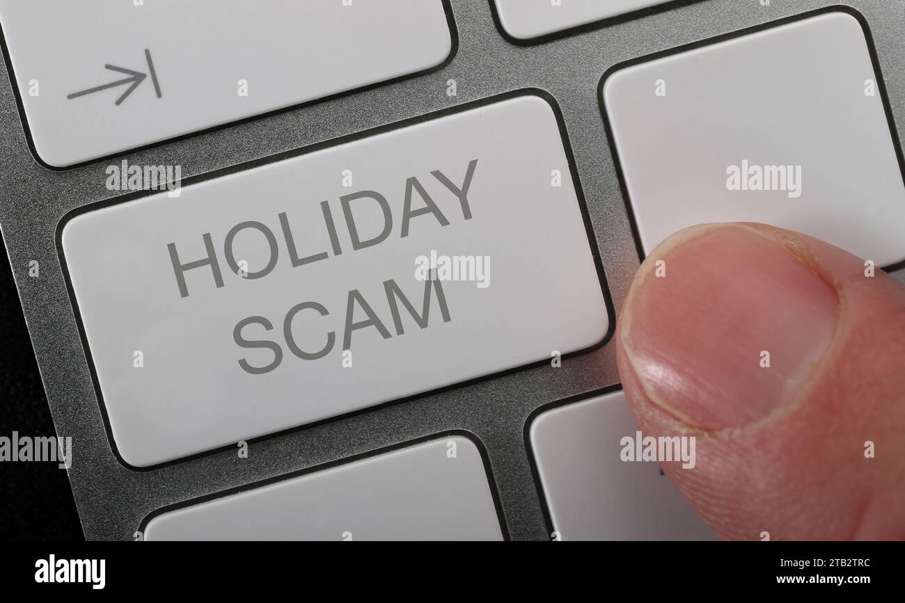 A man pressing a holiday scam button on a compter keyboard to report a fake holiday. Stock Photo