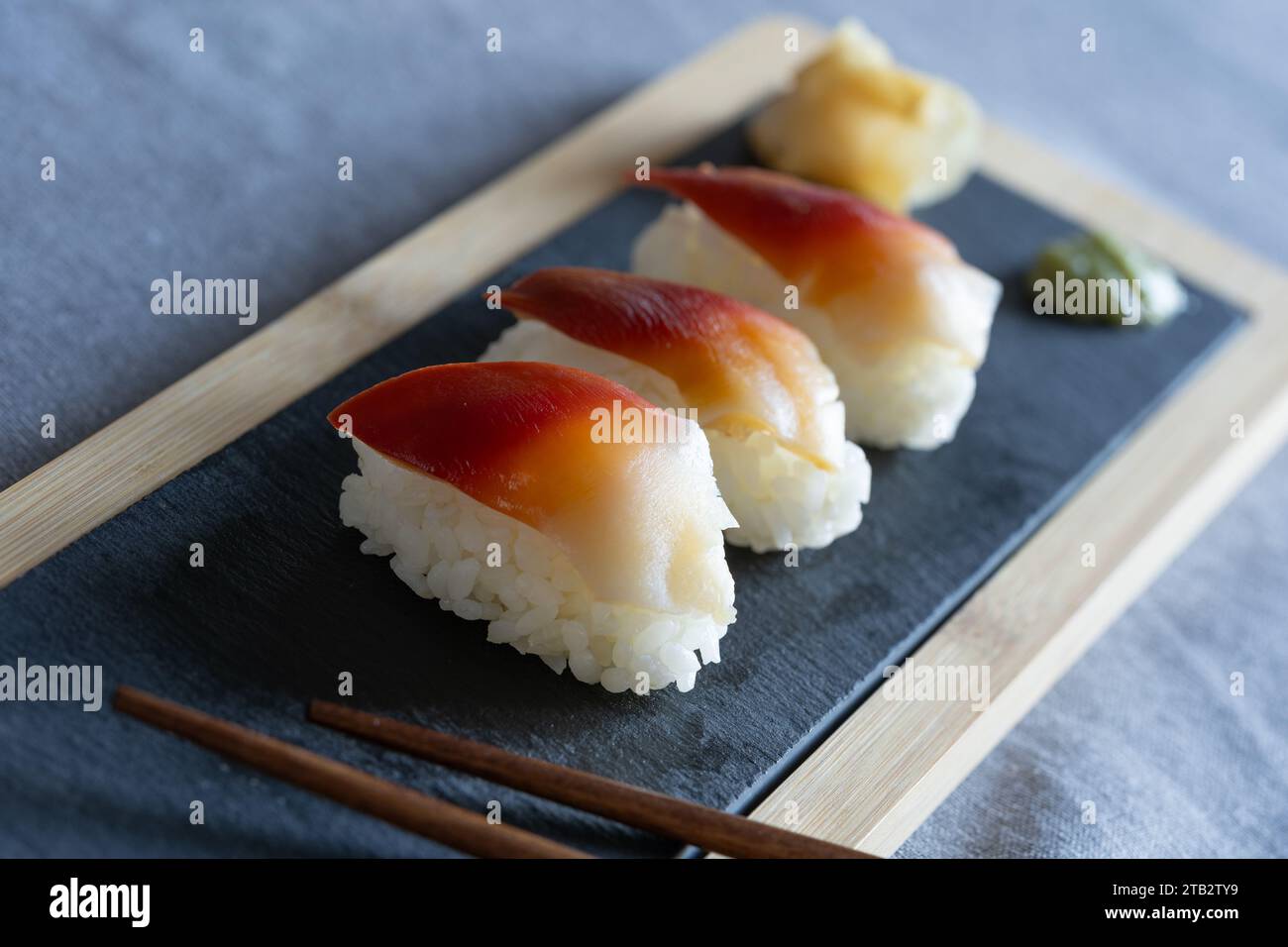 Pieces of homemade surf clam sushi (edible saltwater clam, Japanese: hokki gai) - Japanese style food eaten as a snack on a slate board Stock Photo