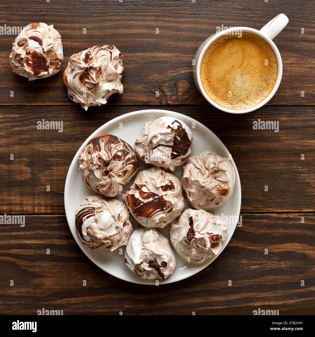 Chocolate meringue cookies and cup of coffee over wooden background. Top view, flat lay Stock Photo