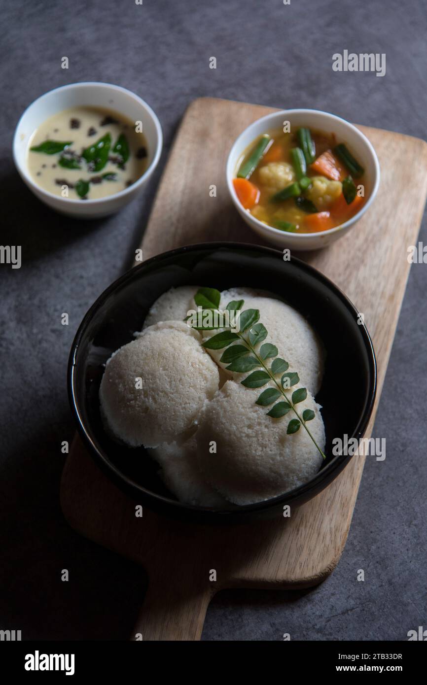 South Indian snacks idli sambar or idly sambhar prepared by steaming fermented rice and served with coconut dip and vegetable soup or sambar. Stock Photo
