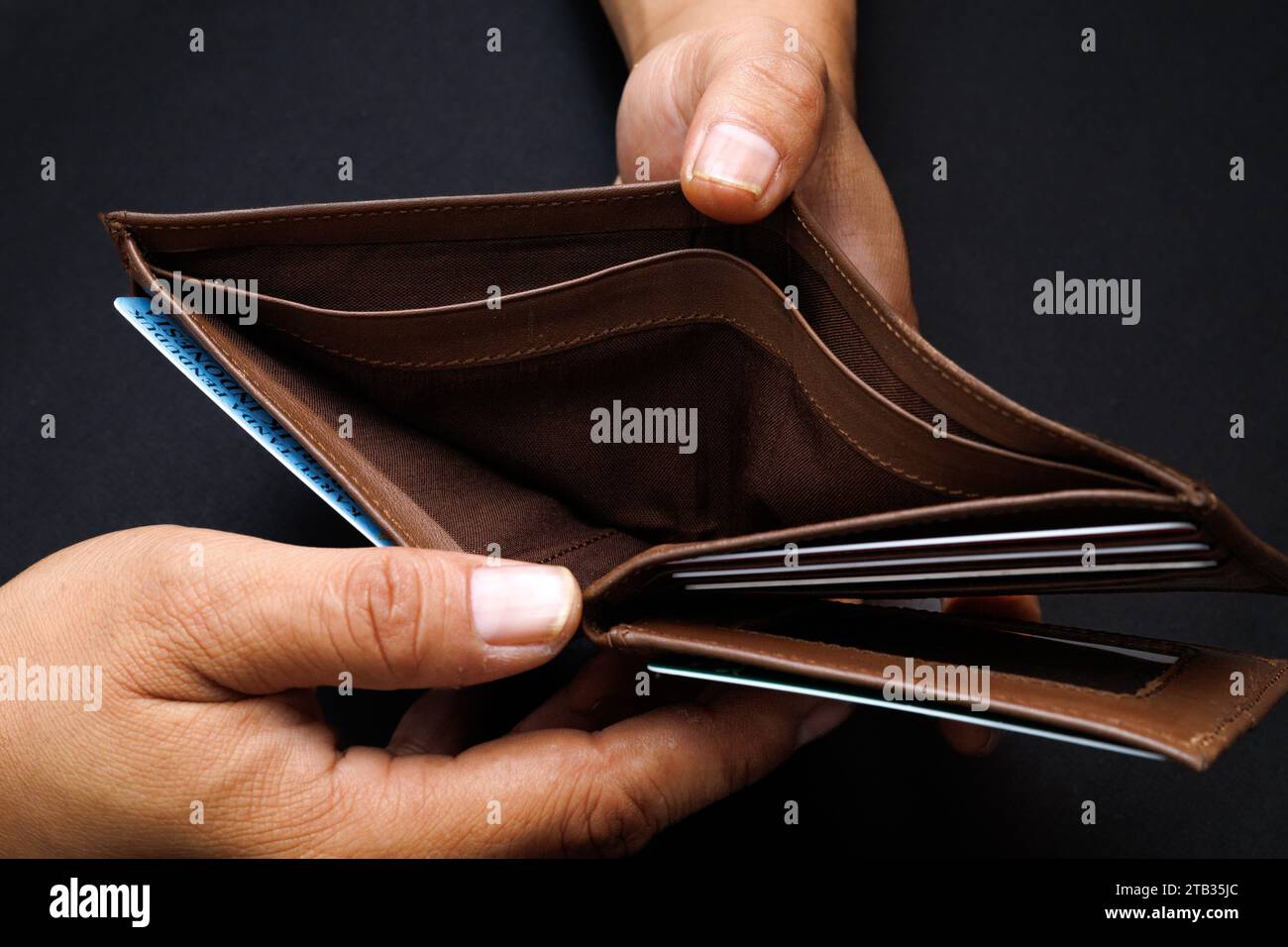 Man hand open an empty wallet isolated on black background. Stock Photo