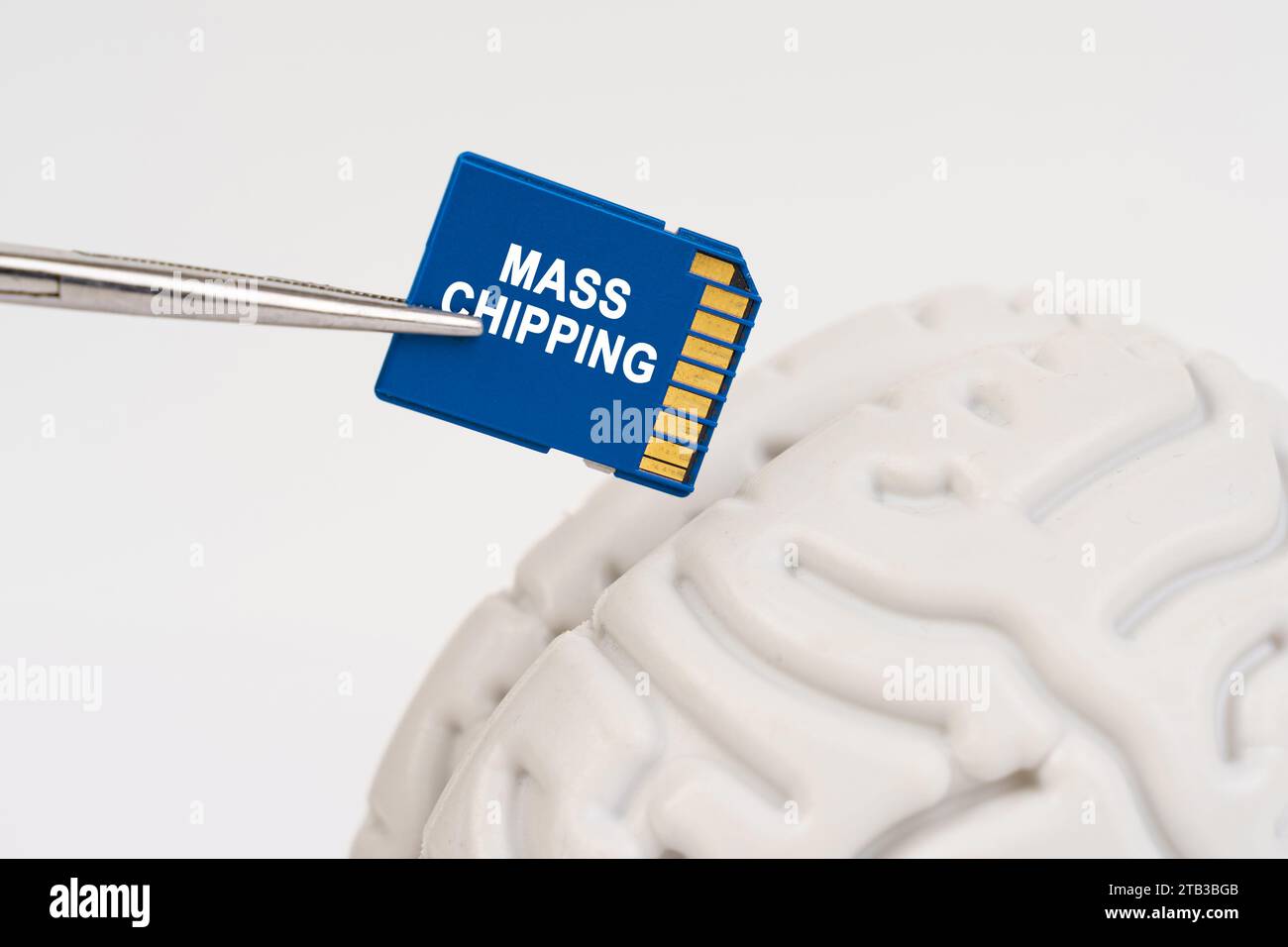 A man inserts a memory card into his brain with the inscription - mass chipping. Science and technology concept. Stock Photo