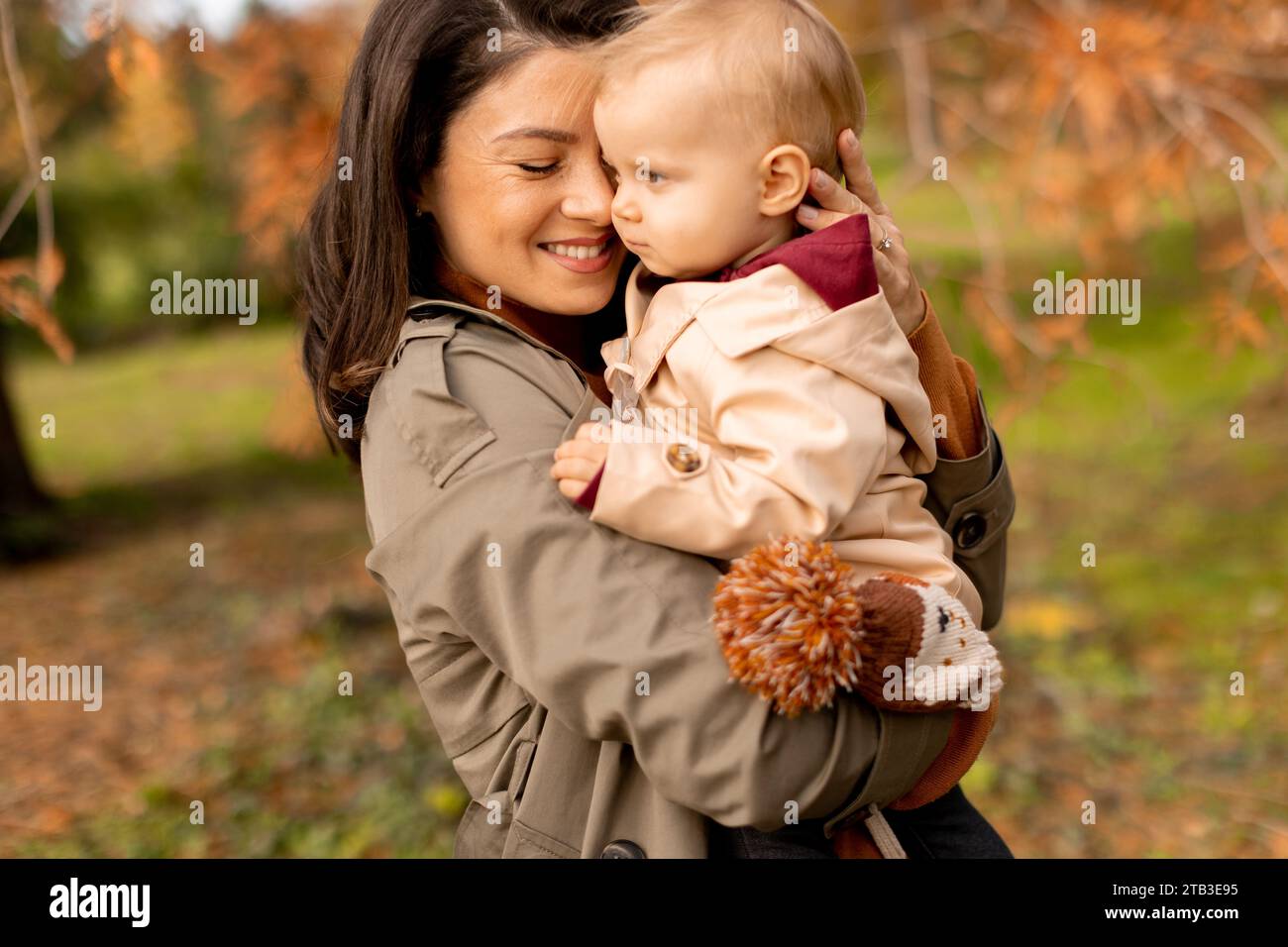 Young woman holding a cute baby girl in the autumn park Stock Photo