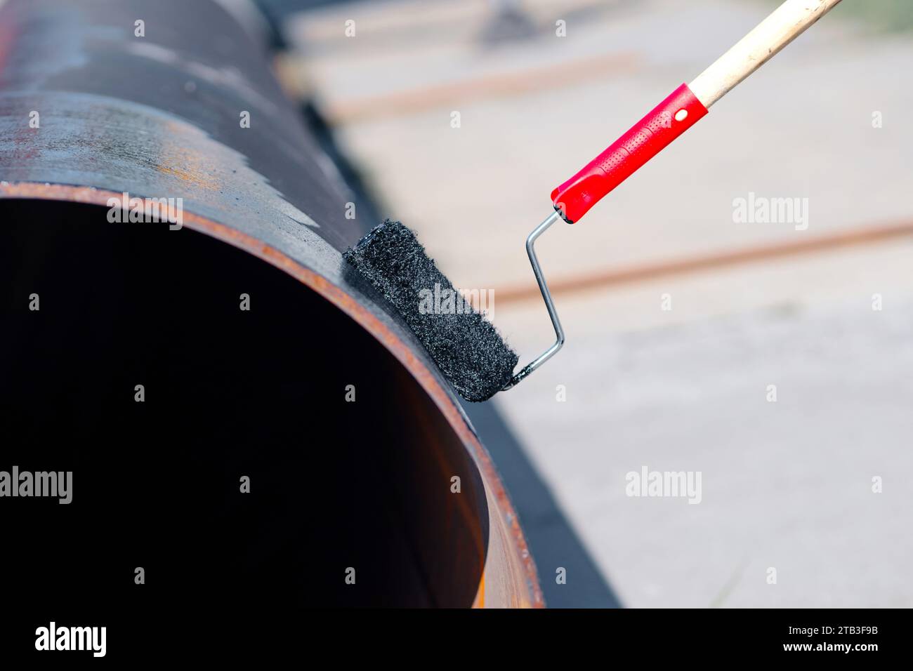 Metal pipe is painted with paint roller with black paint or bitumen