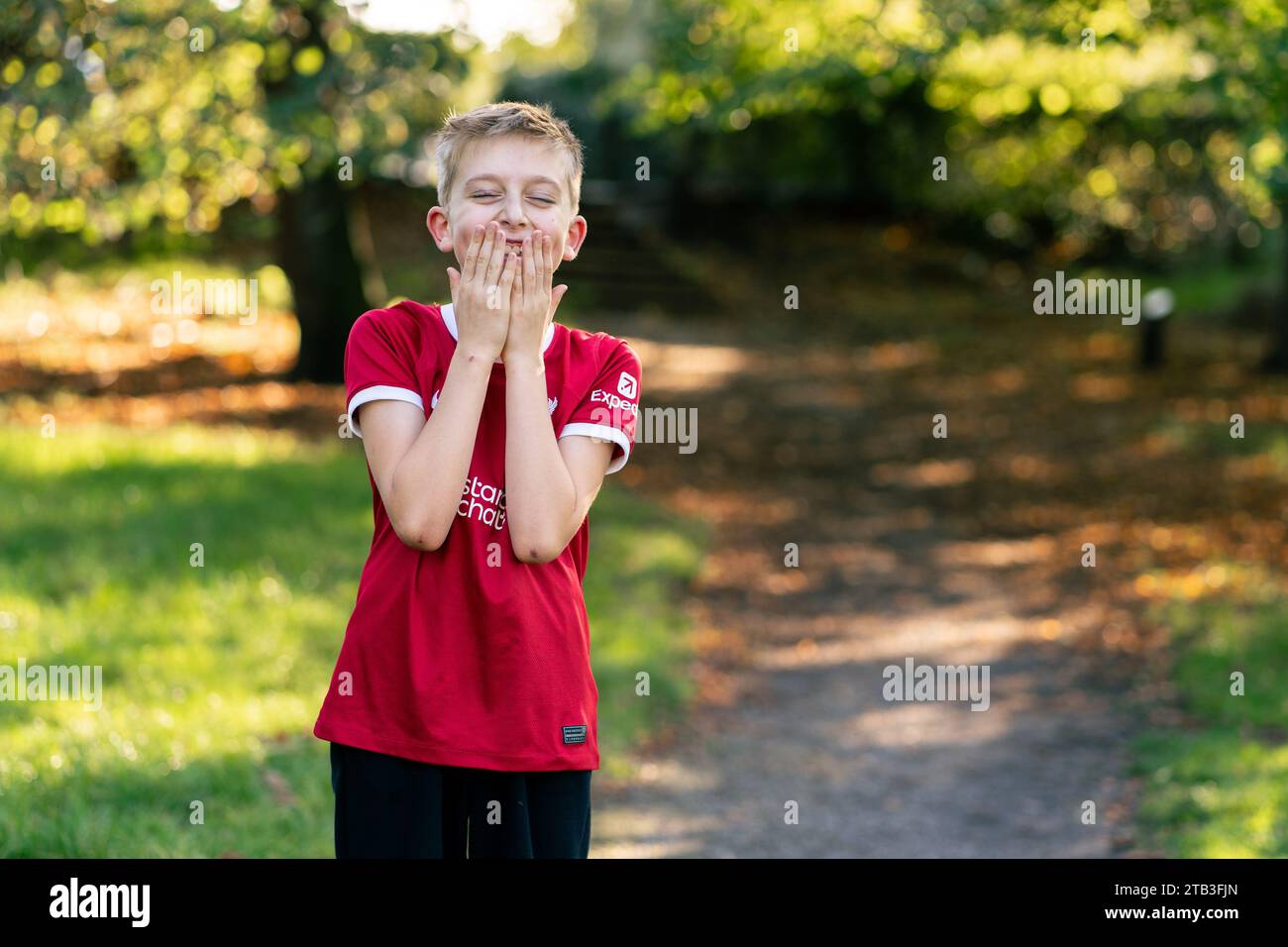 A happy or surprised child in a Liverpool jersey in a park Stock Photo