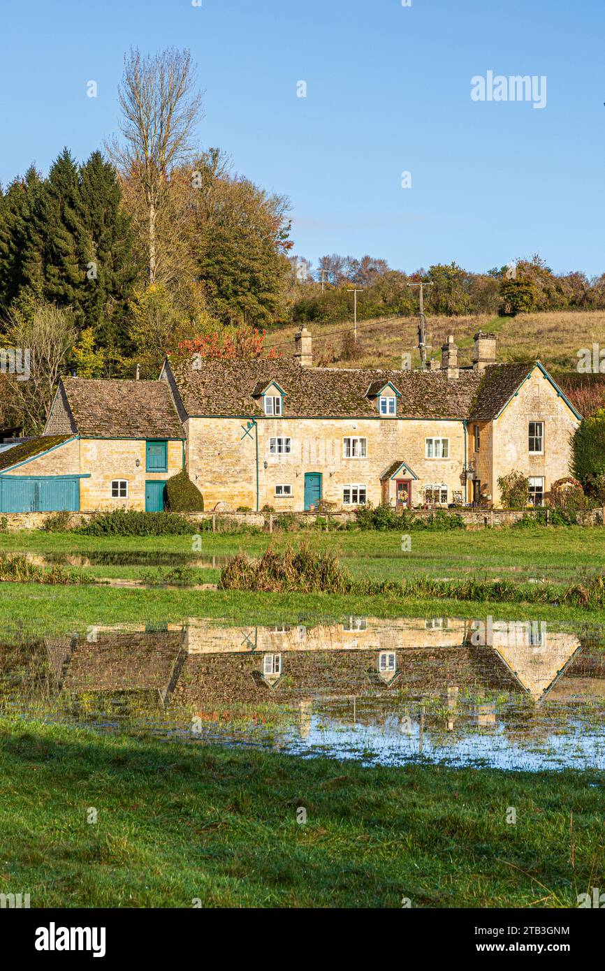 Stowell Mill (or Yanworth Mill) reflected in flood water from the infant River Coln near the Cotswold village of Yanworth, Gloucestershire, England UK Stock Photo