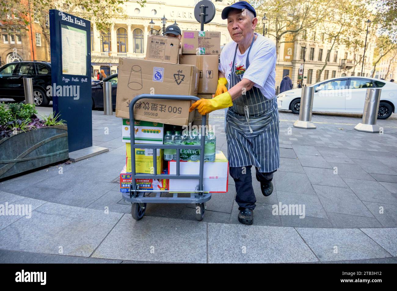 London, UK. Chinese man delivering good to Chinatown on a trolley from Charing Cross Road Stock Photo