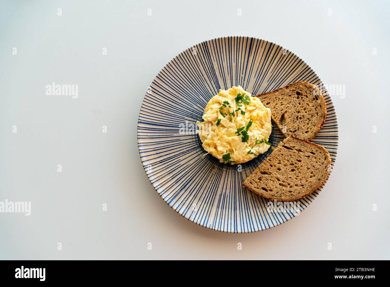 a plate of scrambled eggs served with brown bread toast birds eye view. Stock Photo