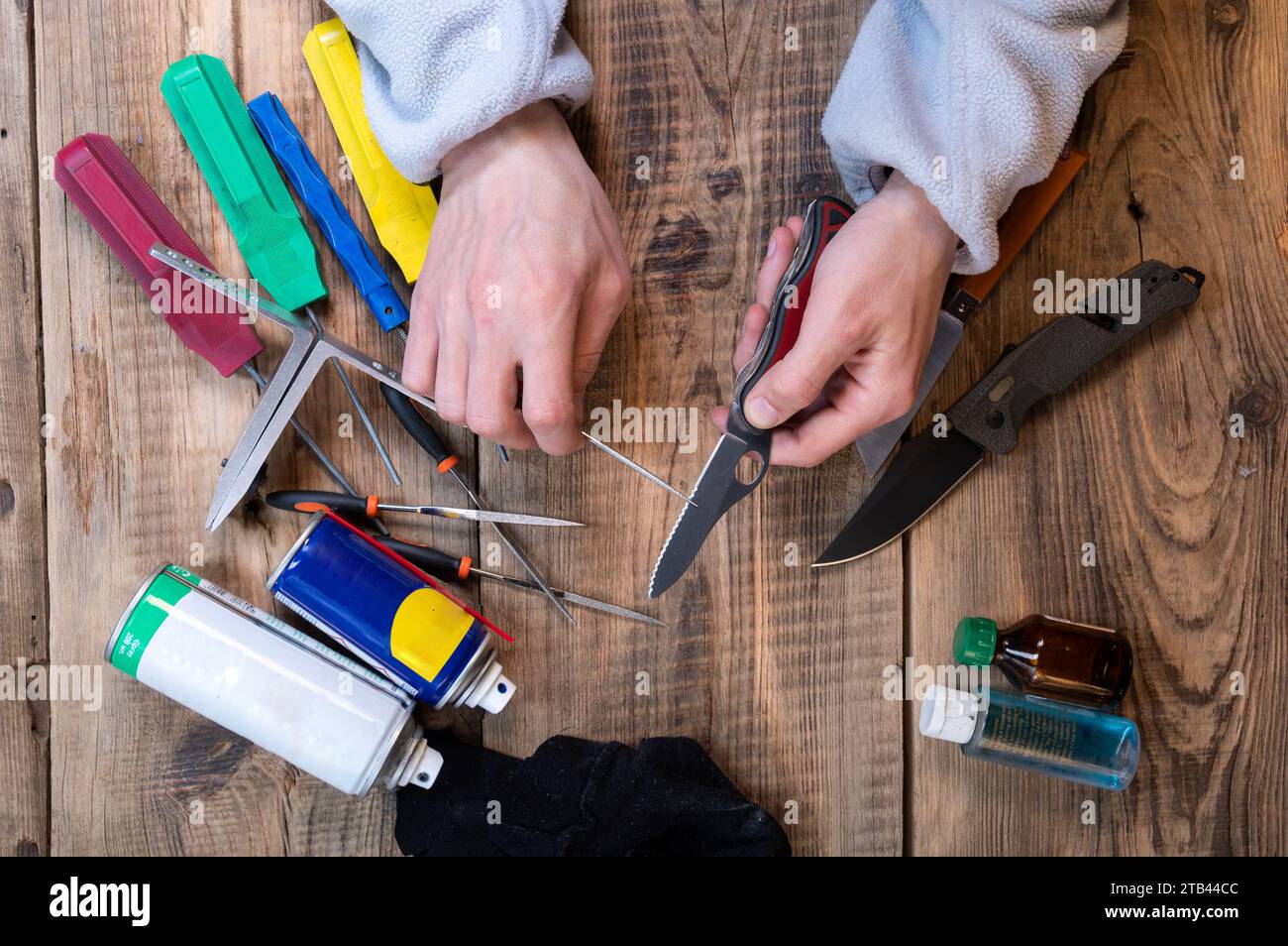 A master sharpens a knife with a serrated blade. Sharpening a serrated