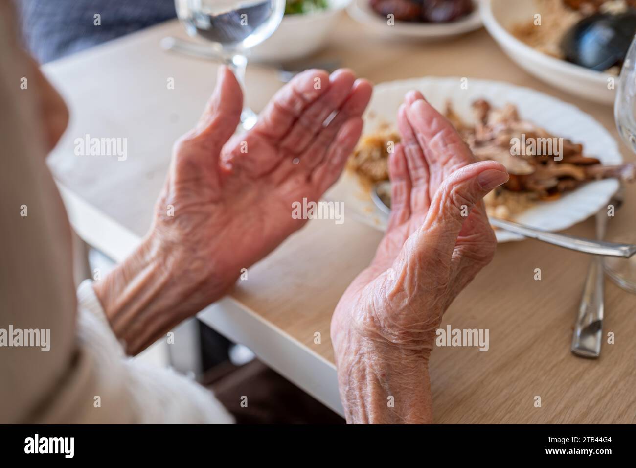 Family eating together with multi generation members in modern living room, praying before eating in ramadan Stock Photo