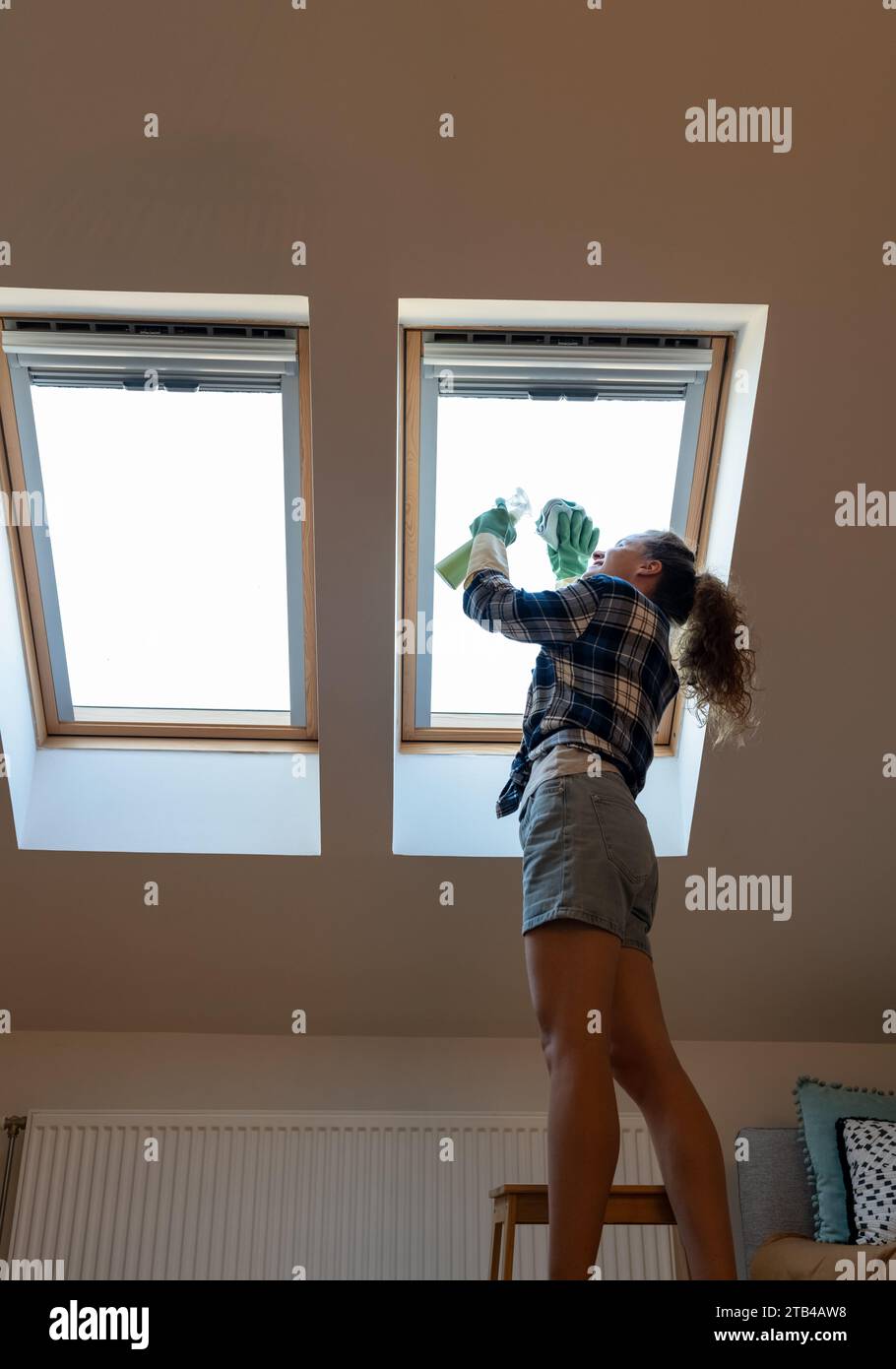 Picture of Woman cleans skylight window in her apartment. Housework, cleaning roof ...