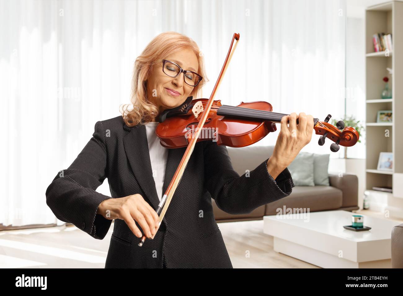 Woman playing a violin at home in a living room Stock Photo