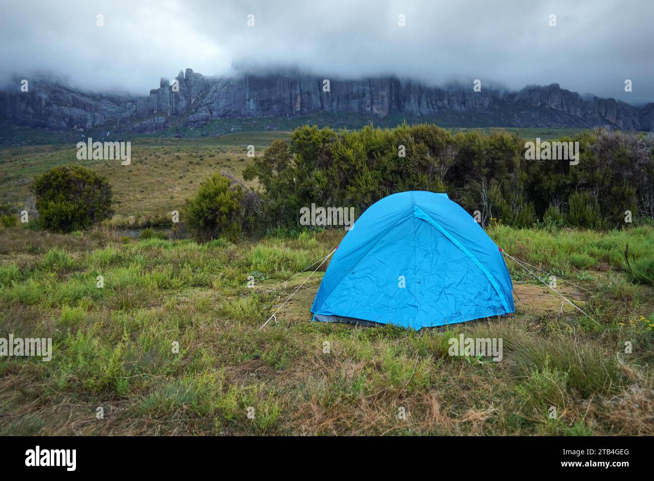Evening mist rolling over mountains, blue tent in foreground - landscape at Pic Boby base camp, typical scenery of Andringitra national park, Madagasc Stock Photo