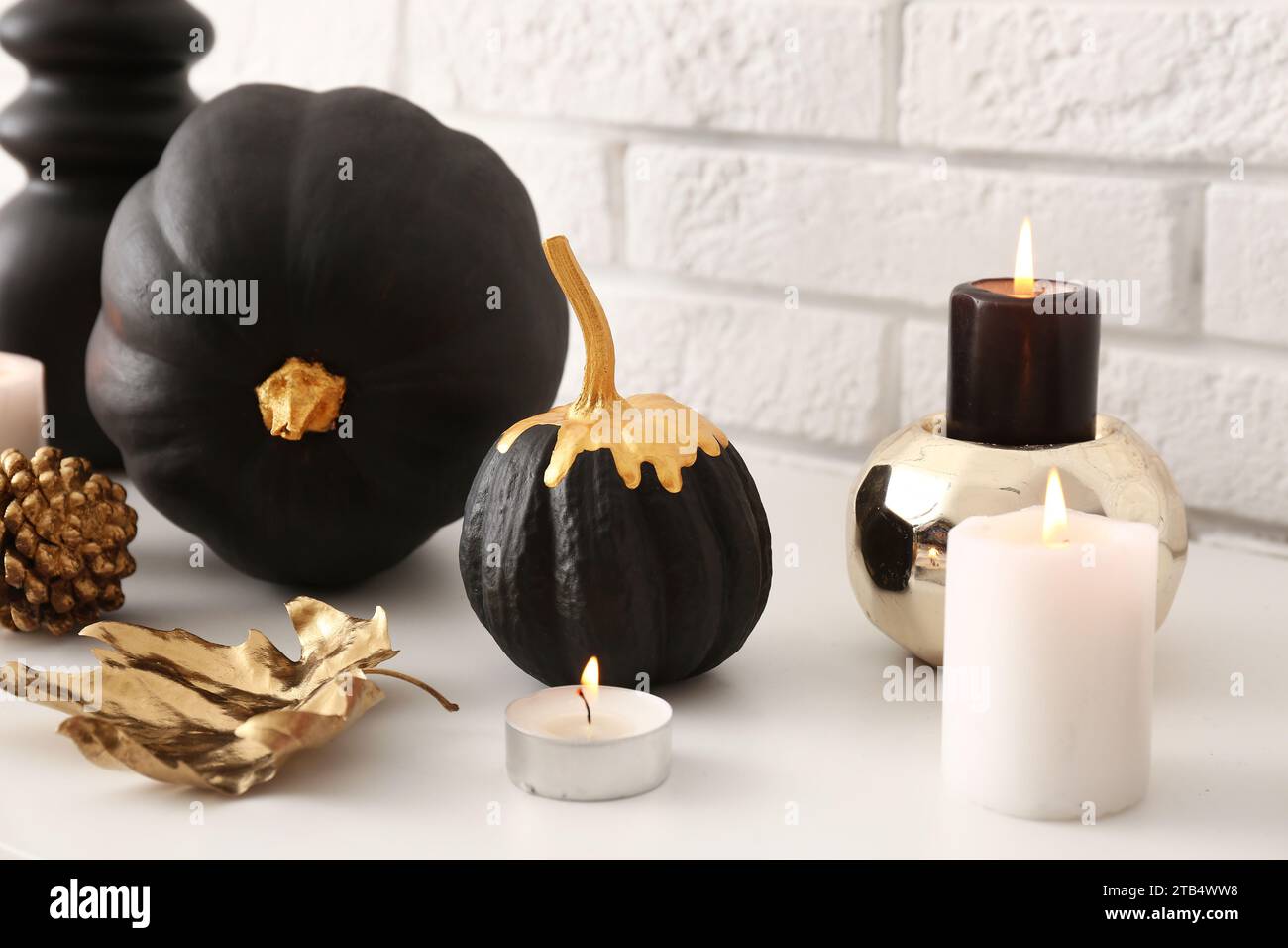 Black painted pumpkins and candles near white brick wall Stock Photo ...
