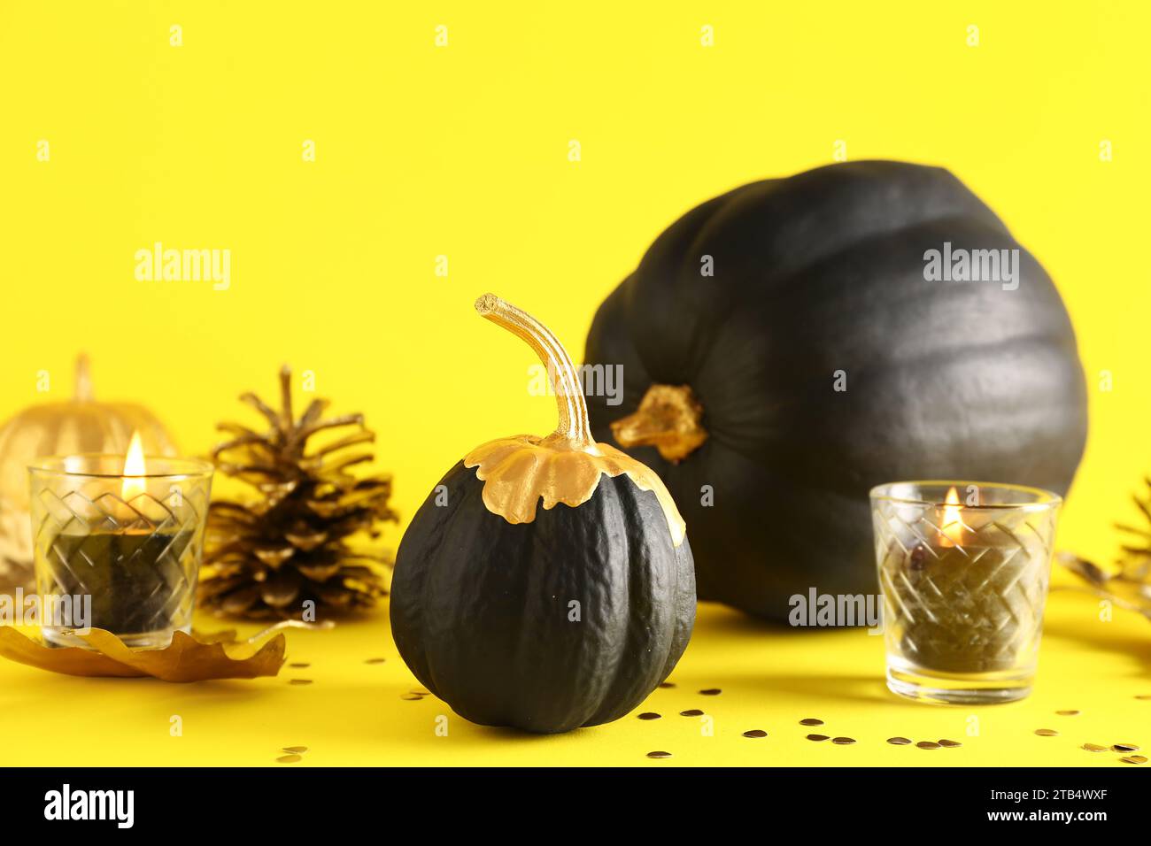 Black painted pumpkins with candles on yellow background Stock Photo ...