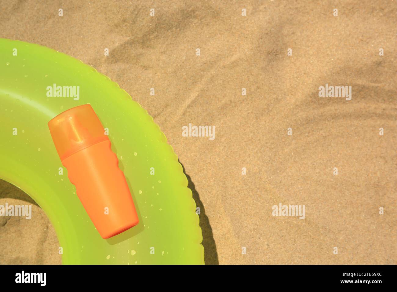 Sunscreen and inflatable ring on sand, top view with space for text. Sun protection care Stock Photo