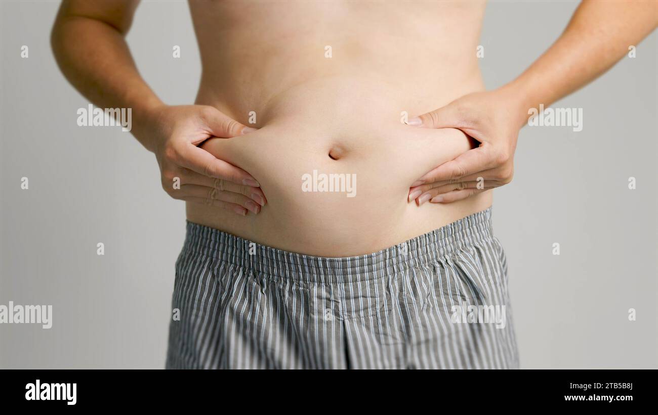 close up of man hand pinching excessive belly fat Stock Photo