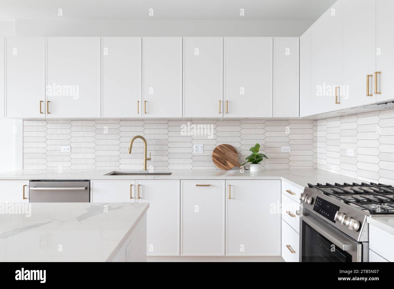 A beautiful kitchen detail with white cabinets, a gold faucet, white marble  countertops, and a brown picket ceramic tile backsplash Stock Photo - Alamy, image size:1300x956