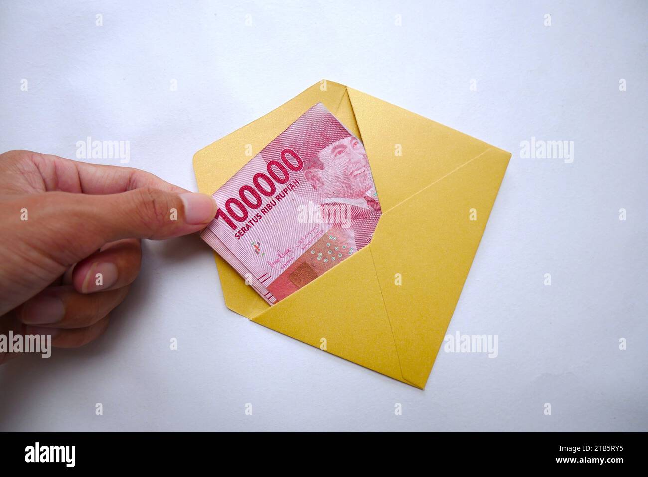 Hand takes money from an envelope on a white background. Rupiah is the currency of Indonesia Stock Photo
