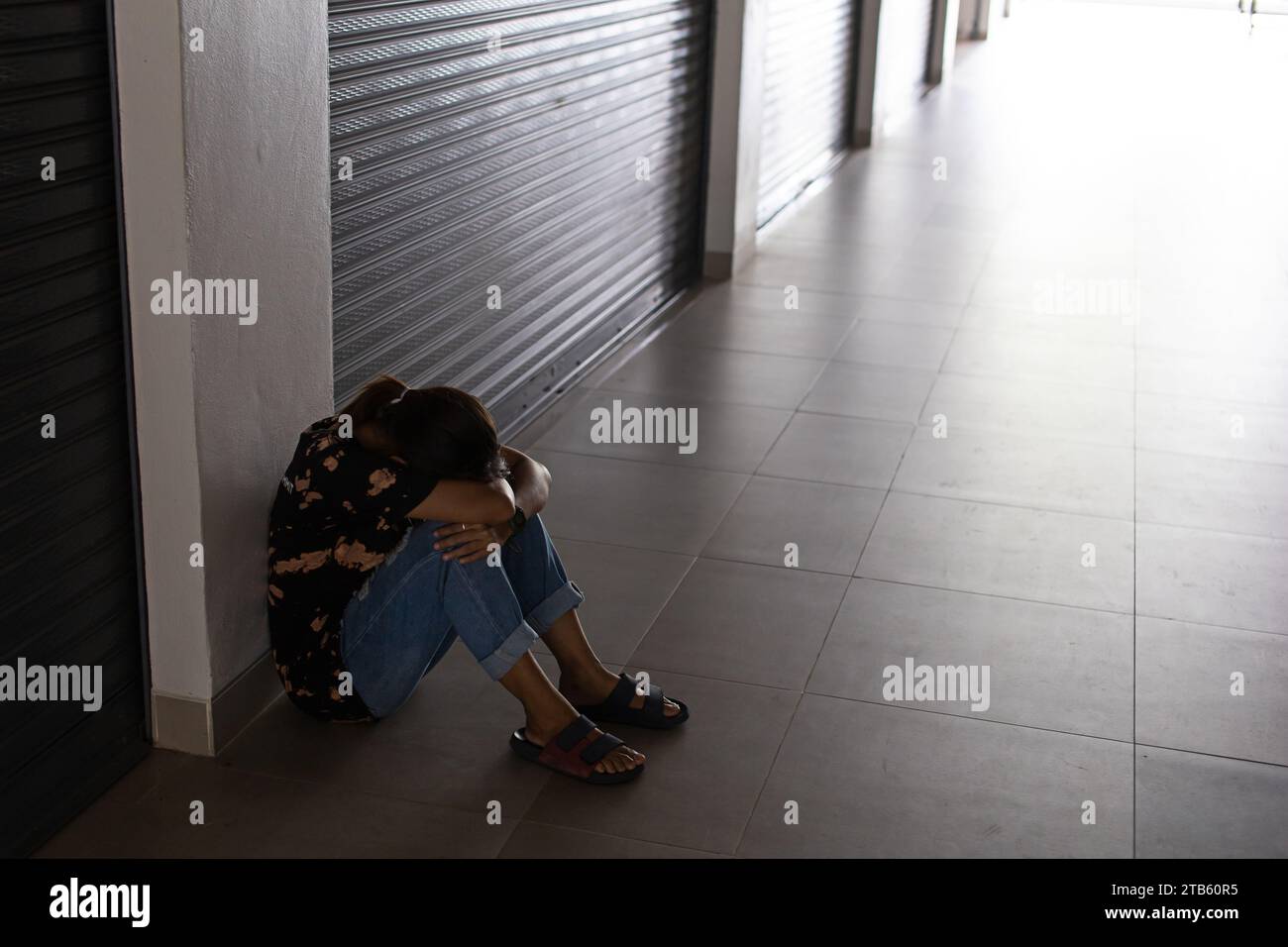 A sad and depressed woman sitting on the floor with her head down, sad mood, feeling tired, lonely and unhappy. spot focus Stock Photo