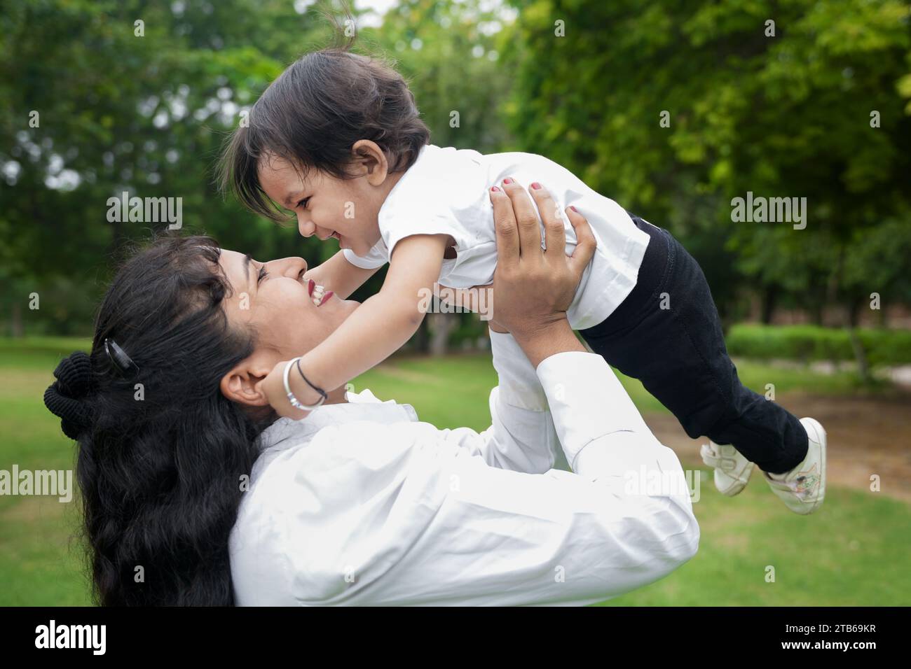 Beautiful Young indian mom throwing baby girl up in air and catching
